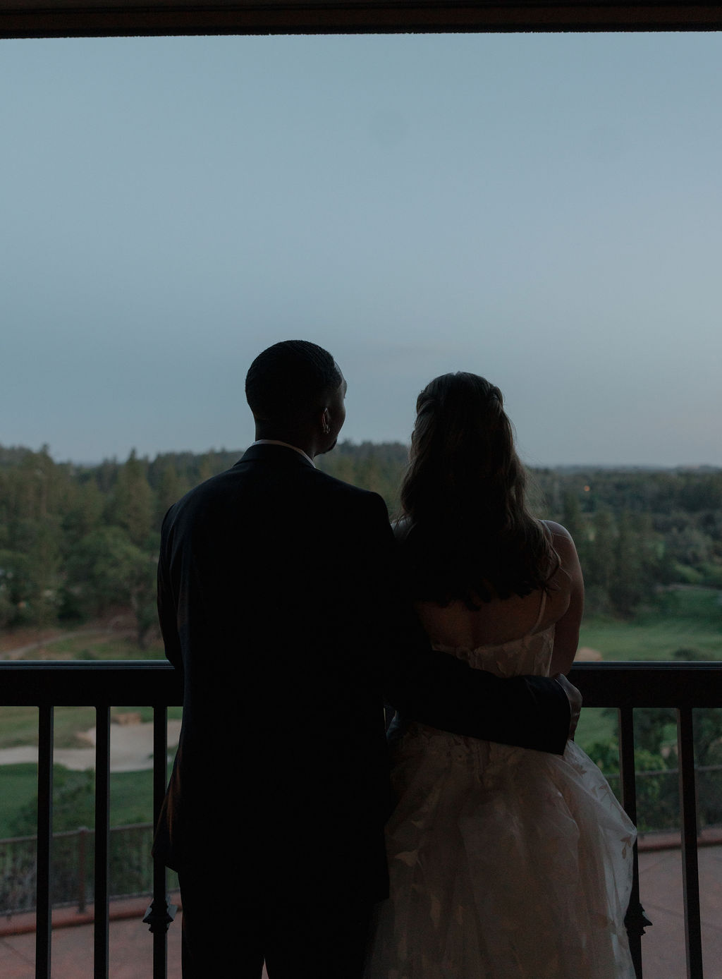 A bride and groom looking out at the views from their wedding venue