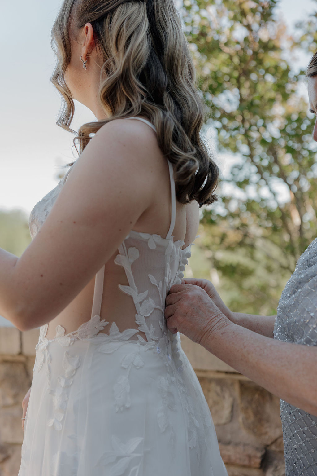 A bride getting her wedding dress buttoned